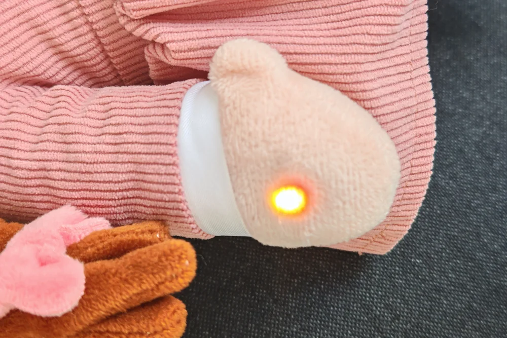 La même main, avec le voyant allumé en jaune pendant que la peluche répond