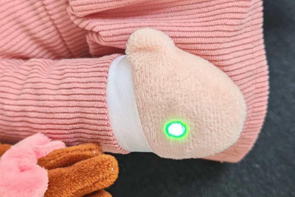 La main de la peluche Playnitive, avec le voyant allumé en vert
