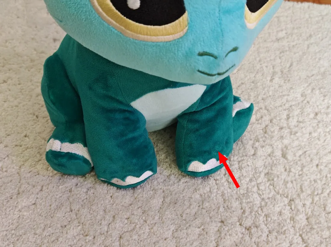 Le bouton dans la main de la peluche, indiqué par une flèche